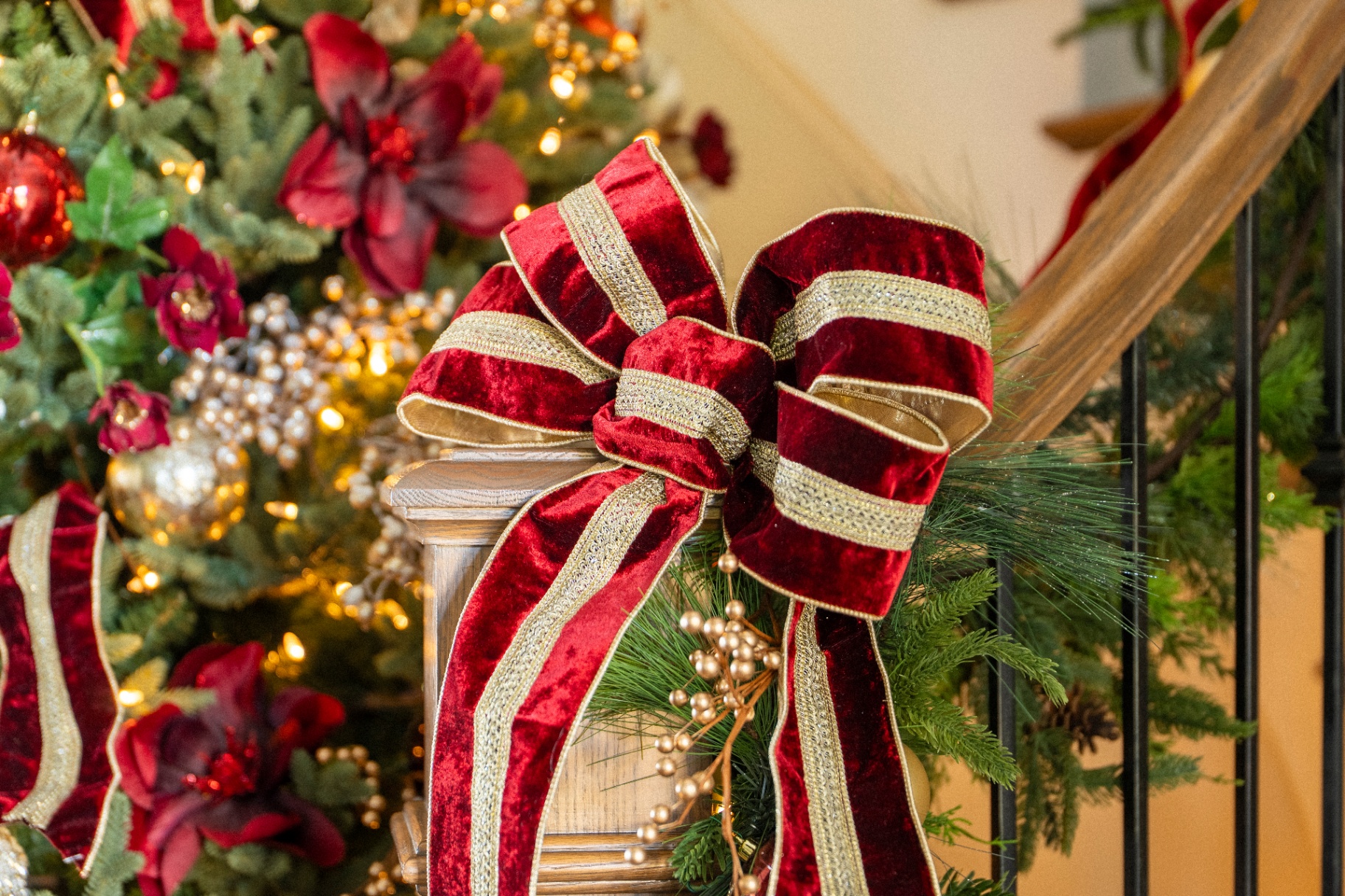 Velvet burgundy and gold ribbon tied at the staircase newel