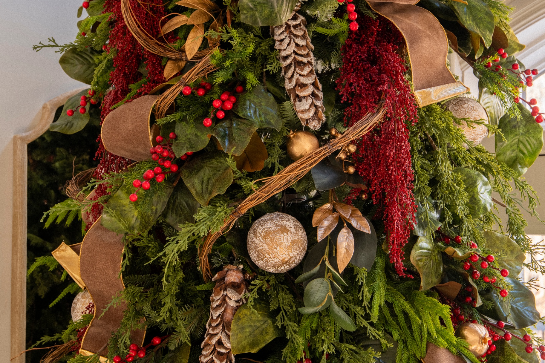 Close-up of a tree with pinecones, red berry sprays, and velvet ribbon