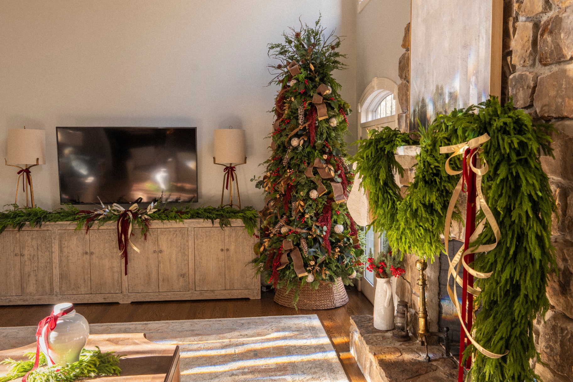 Christmas tree and fresh evergreen mantle styling in a stone fireplace living room