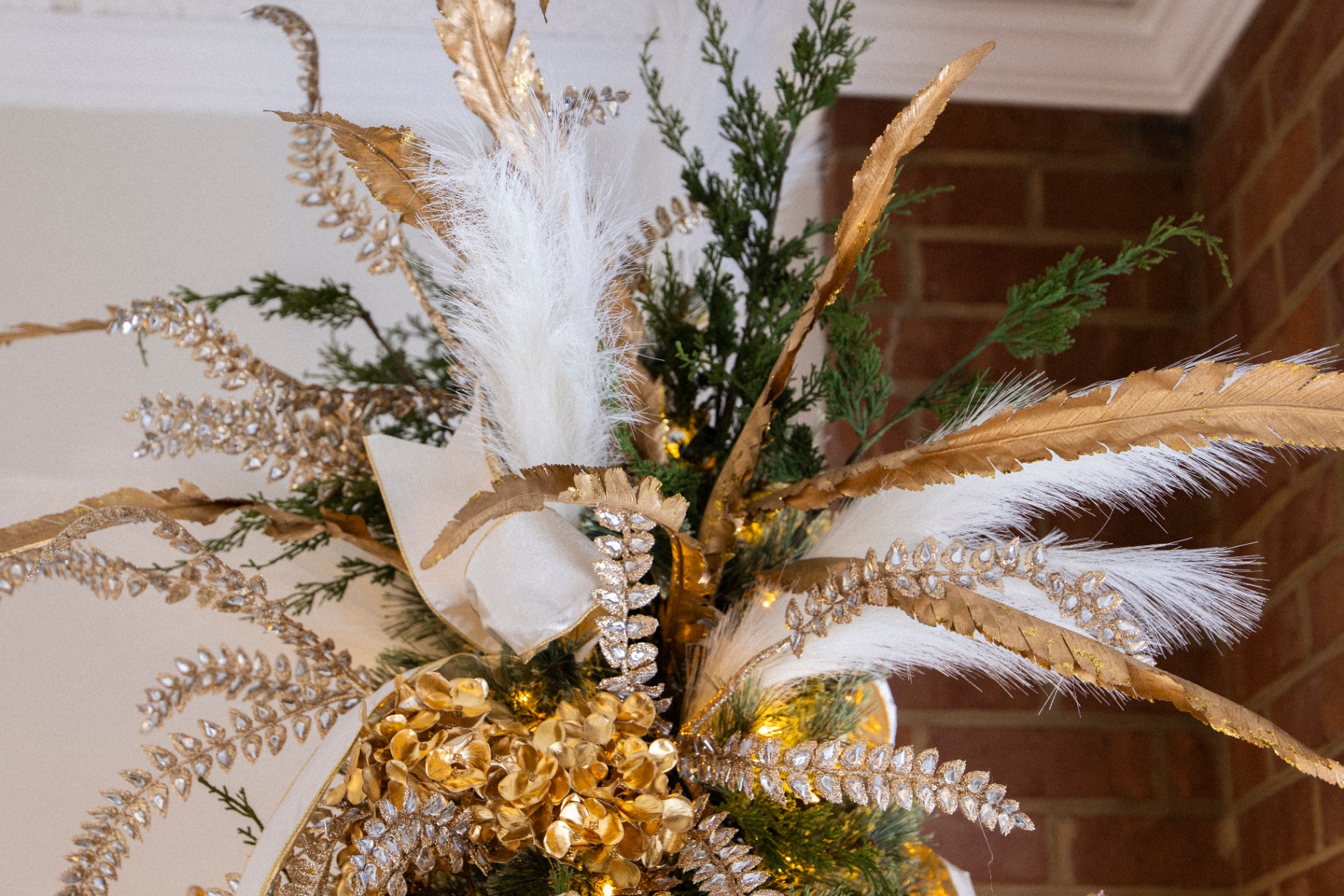 Close-up of gold and white feather ornaments and jeweled branches on a Christmas tree