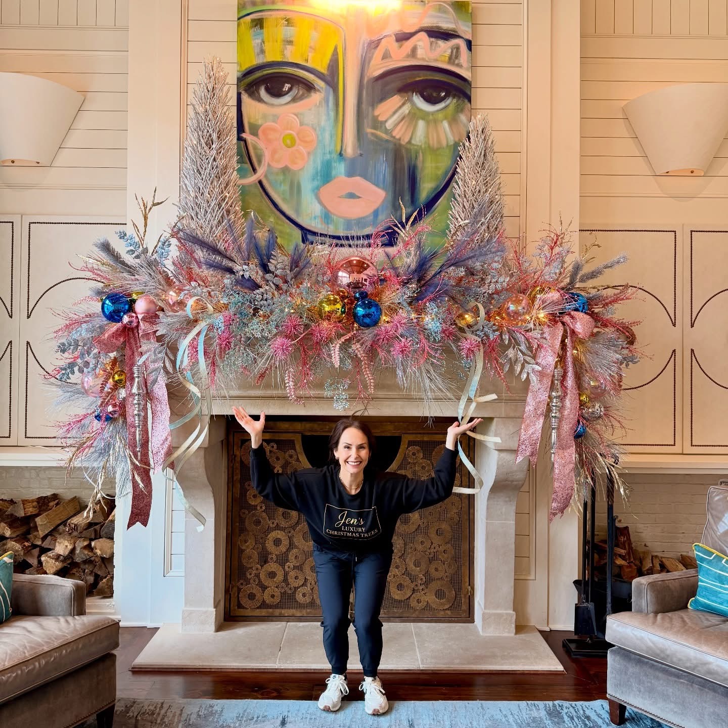 Jen smiling in front of a grand pastel tinsel mantle with blue and pink ornaments and cascading ribbon